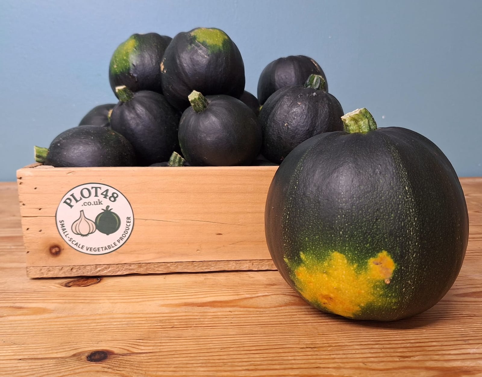A crate of gem squash picked on the farm, with one on the table beside it